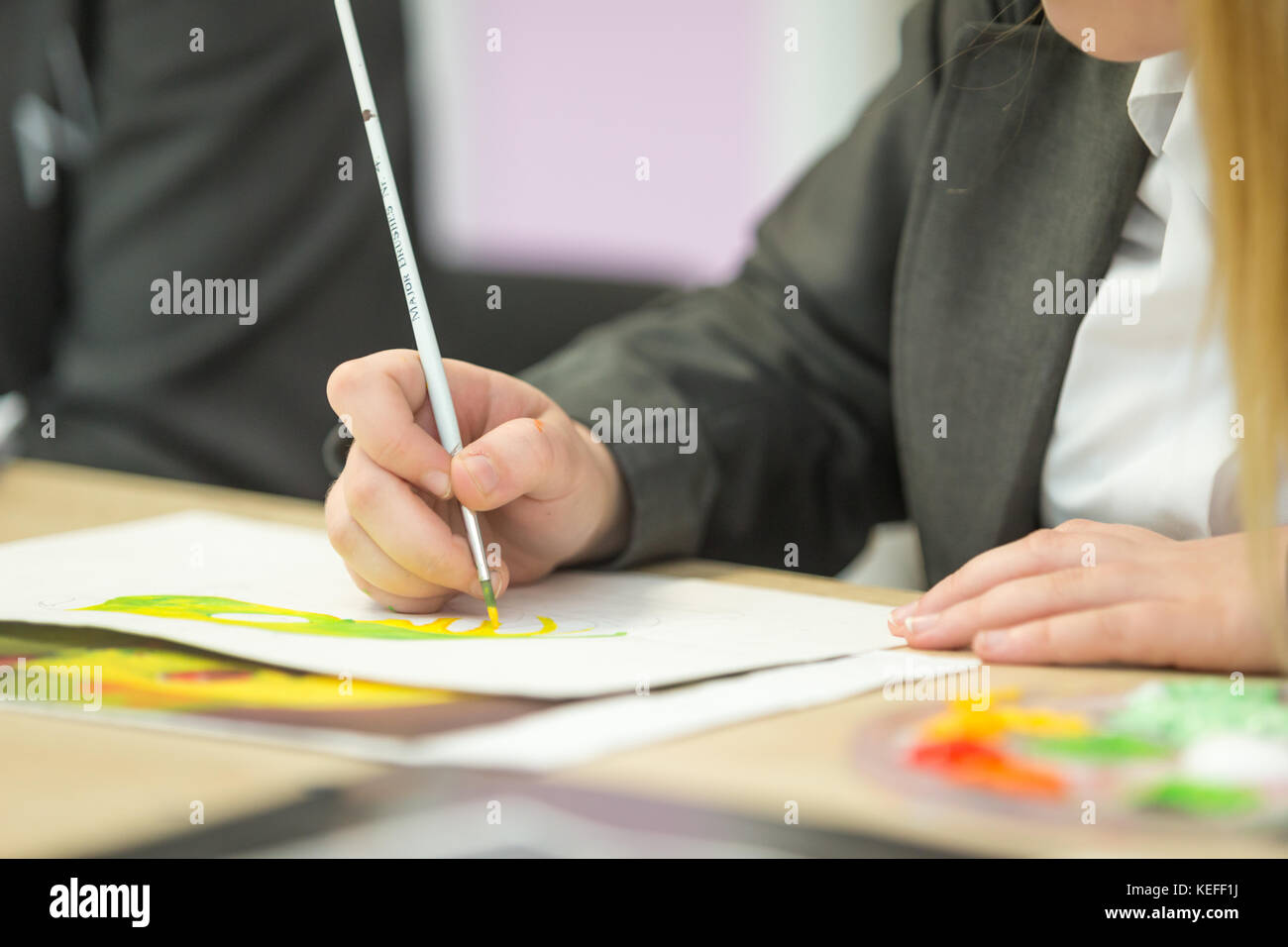 Pupil in a UK state secondary school painting in an art lesson Stock Photo
