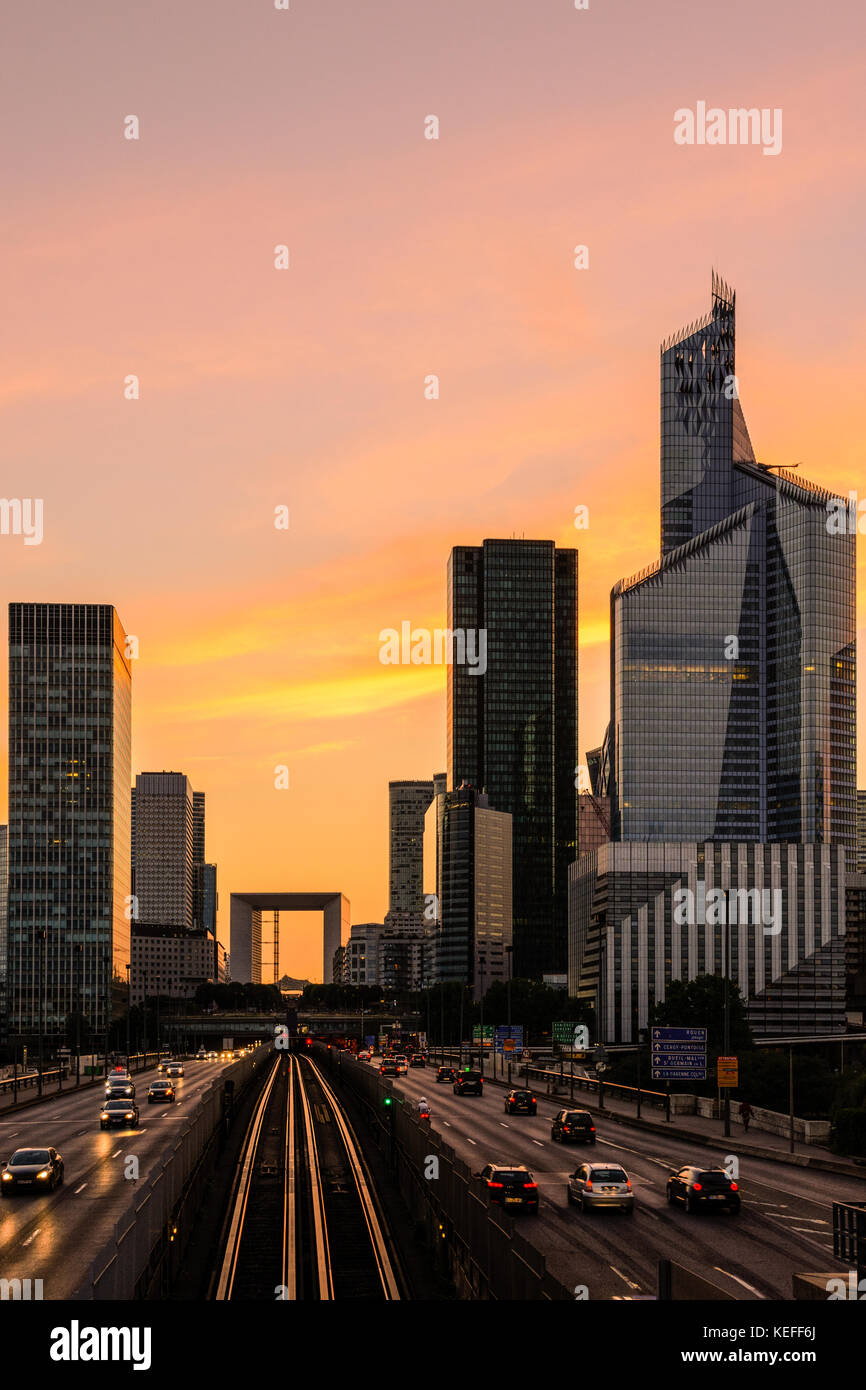 Skyline of Paris La Defense business district with the Grande Arche standing out against a glowing red sky. Stock Photo