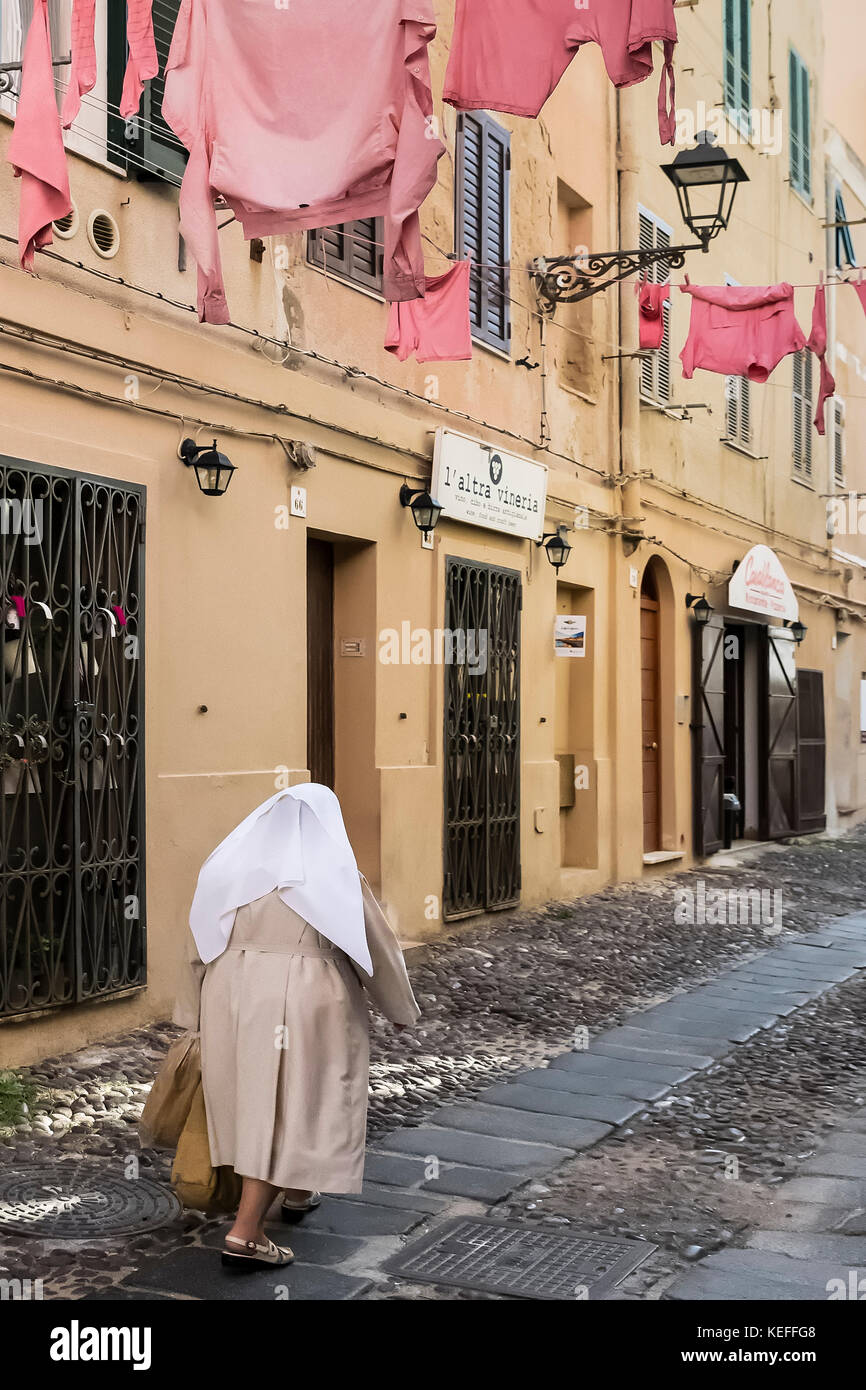Nun walks along a cobblestone street, Alghero, Sardinia, Italy. Stock Photo
