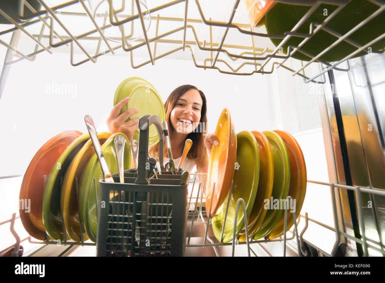 Young Happy Woman Arranging Plates In Dishwasher Stock Photo