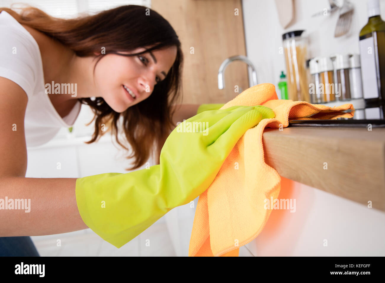 Close-up Of Young Woman Cleaning Induction Stove In The Kitchen At Home Stock Photo