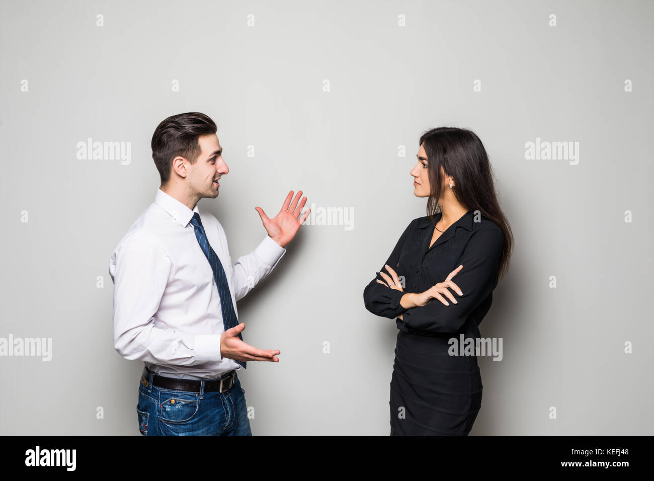 Smiling businesswoman and businessman are conversing against grey Stock Photo