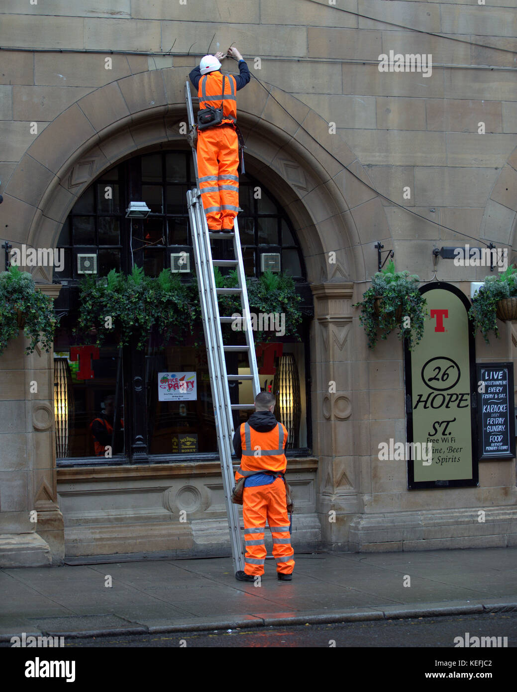 two men and a ladder electricians or workmen moving cables on hope street glasgow Stock Photo