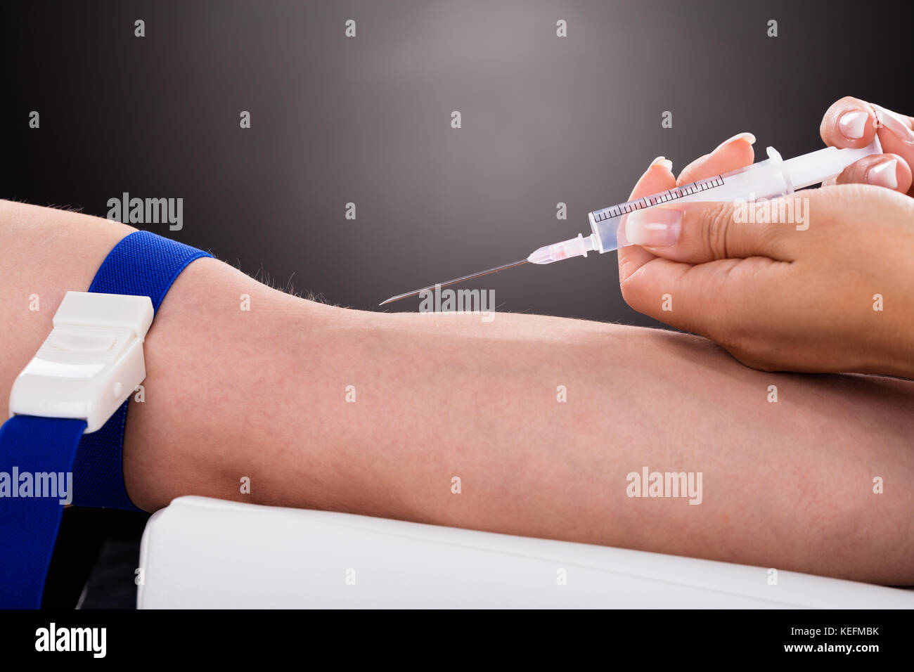 Close-up Of A Doctor Checking Blood Sample From Patient's Arm Stock Photo