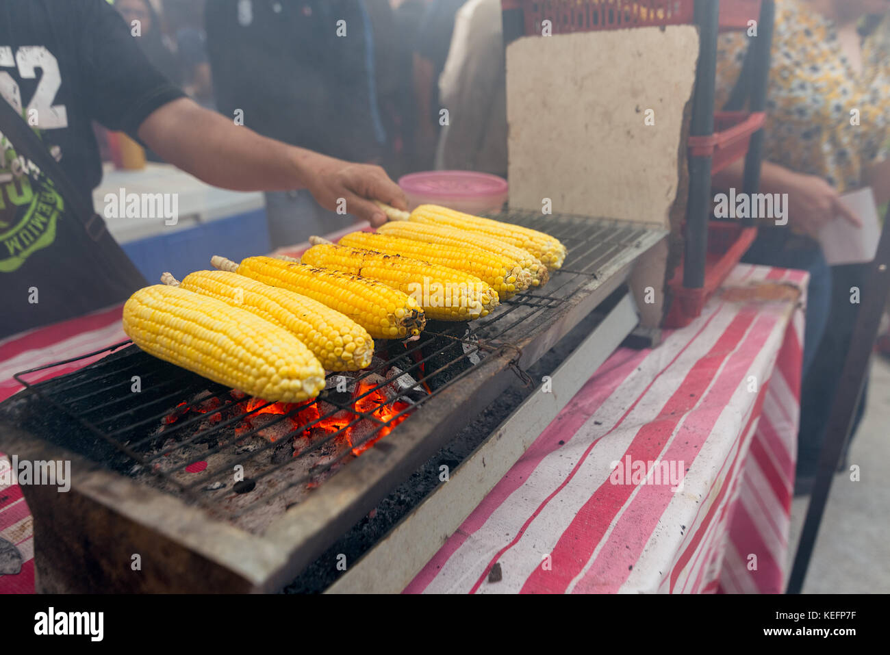 Corn on the cob cooking over a charcoal grill on an asian street food
