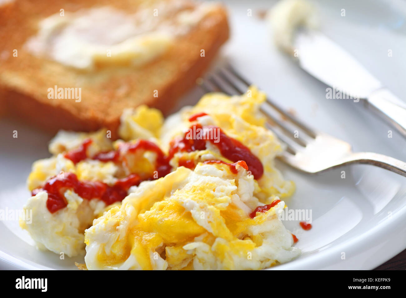 Scrambled eggs with Sriracha hot chili sauce and buttered toast Stock