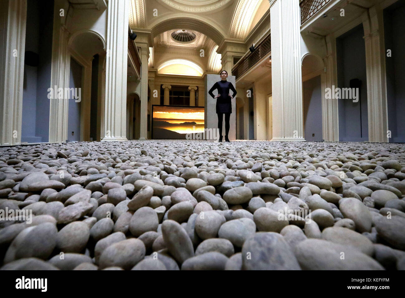 Kathryn Dunlop of Edinburgh University views thousands of dark pebbles taken from Scottish riverbeds which have transformed the university&Atilde;•s Talbot Rice Gallery as part of work by acclaimed artist and filmmaker John Akomfrah in his first solo exhibition 'Vertigo Sea' in Scotland, which opens Saturday 21st and runs until the end of January 2018. Stock Photo