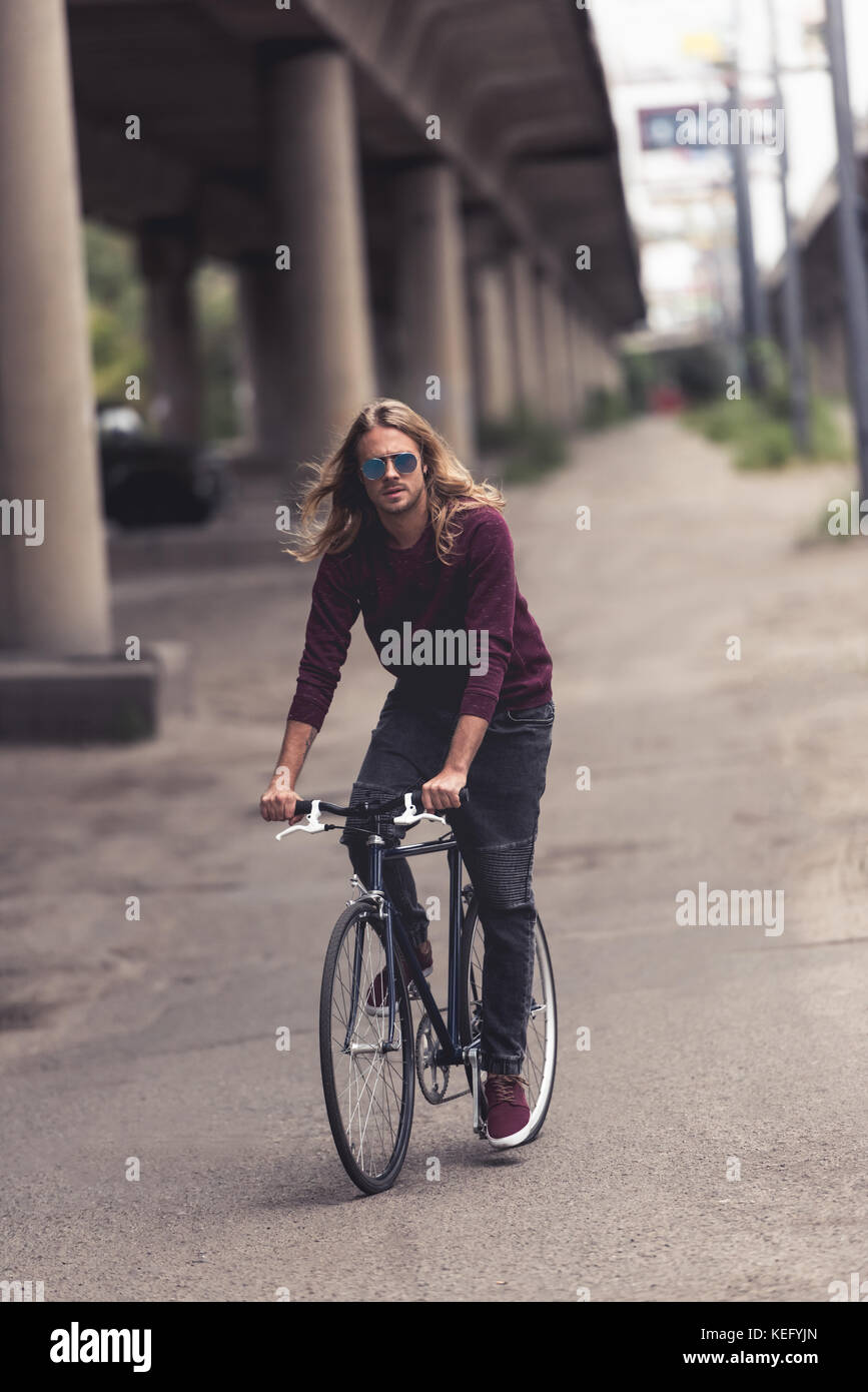 handsome young man with long hair riding vintage bicycle Stock Photo - Alamy