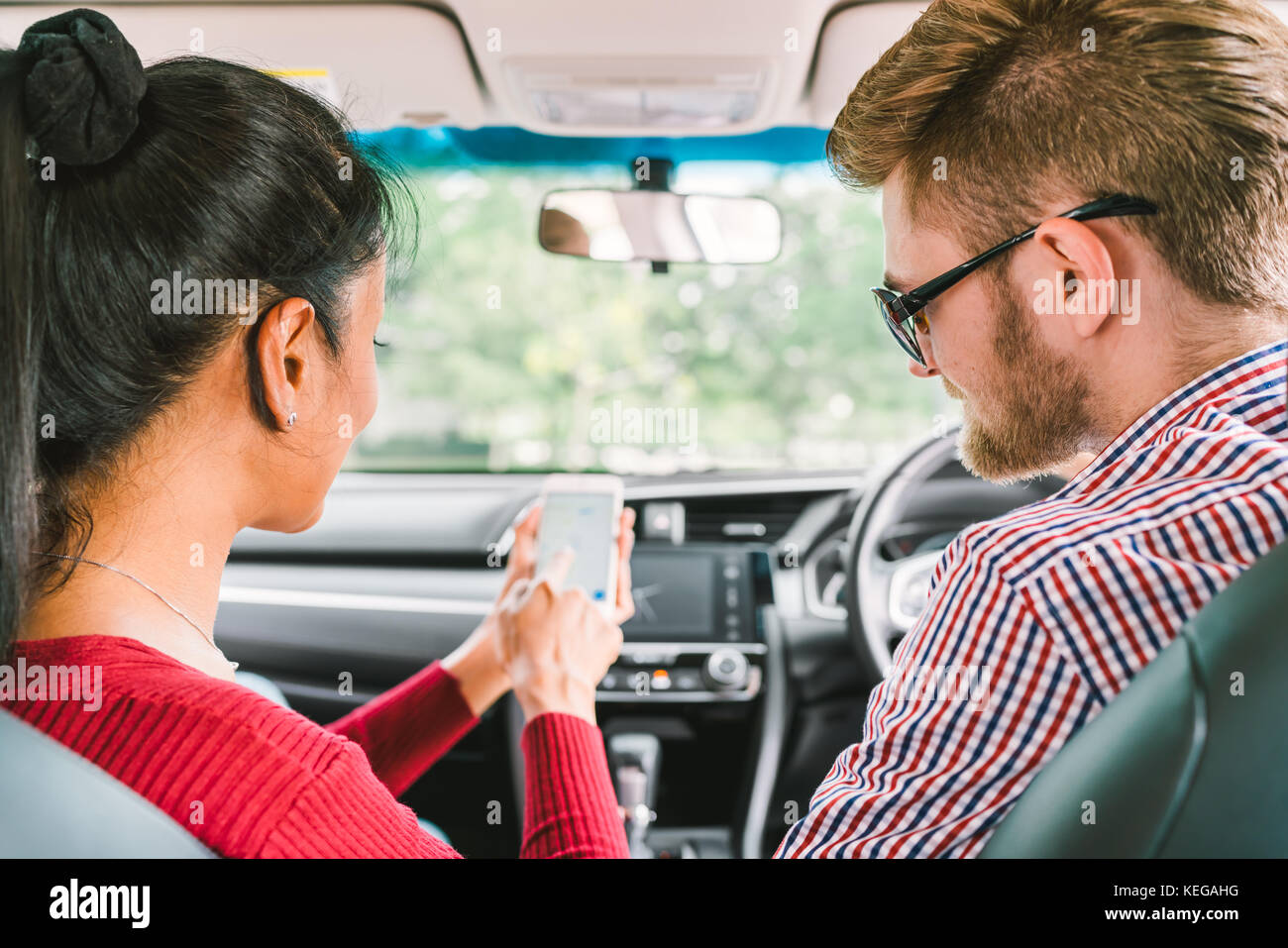 Multiethnic lover couple, white man and black Asian girl using navigator system app on smart phone in car. Modern gadget lifestyle, family travel Stock Photo
