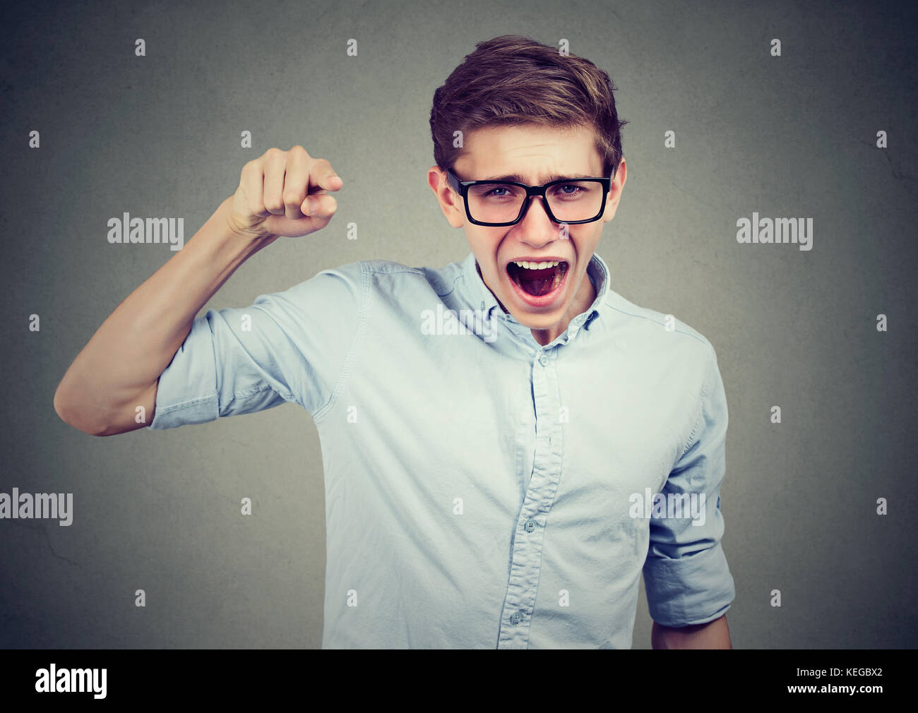 Angry teenager man accusing someone screaming pointing finger at camera Stock Photo