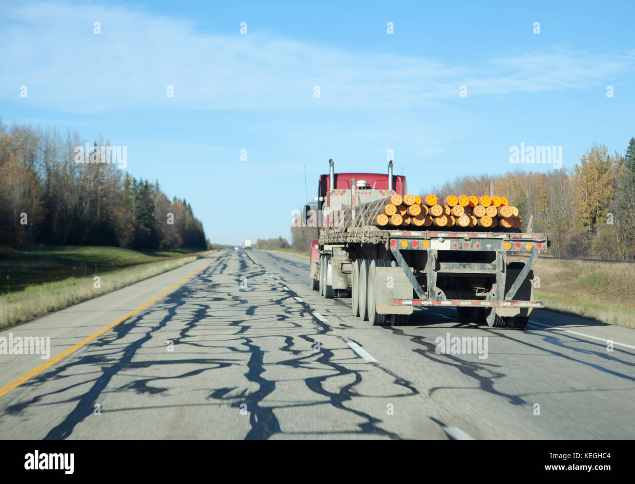 a transfer or 18 wheeler carrying pipes on a highway in blue sky Stock Photo