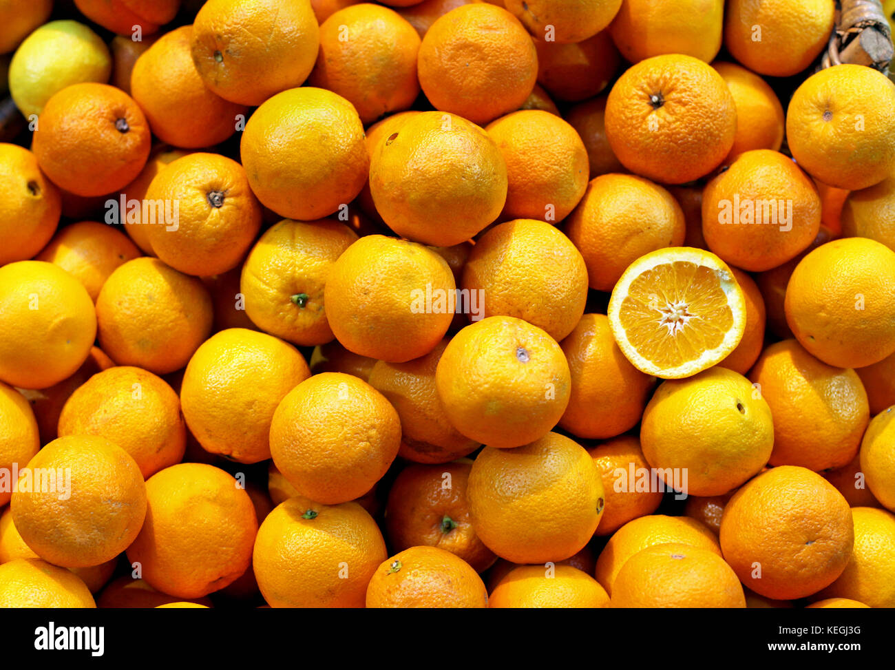 Big pile of fresh oranges with one on the top cut in half Stock Photo