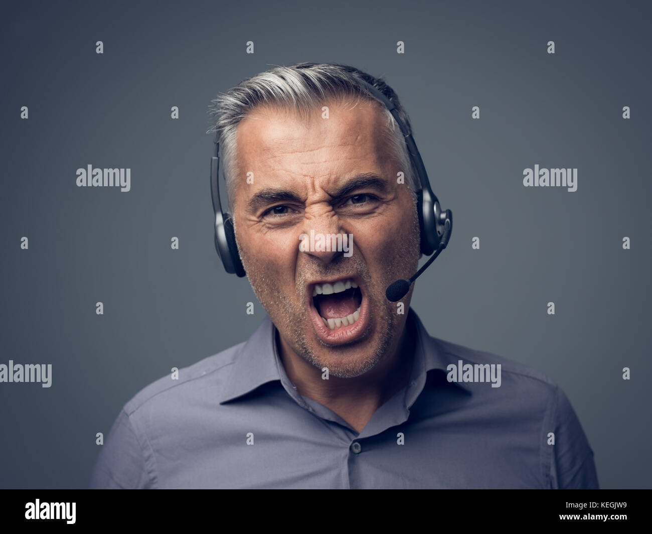 Angry aggressive customer support phone operator with headset, he is yelling and having a dicussion with a customer Stock Photo