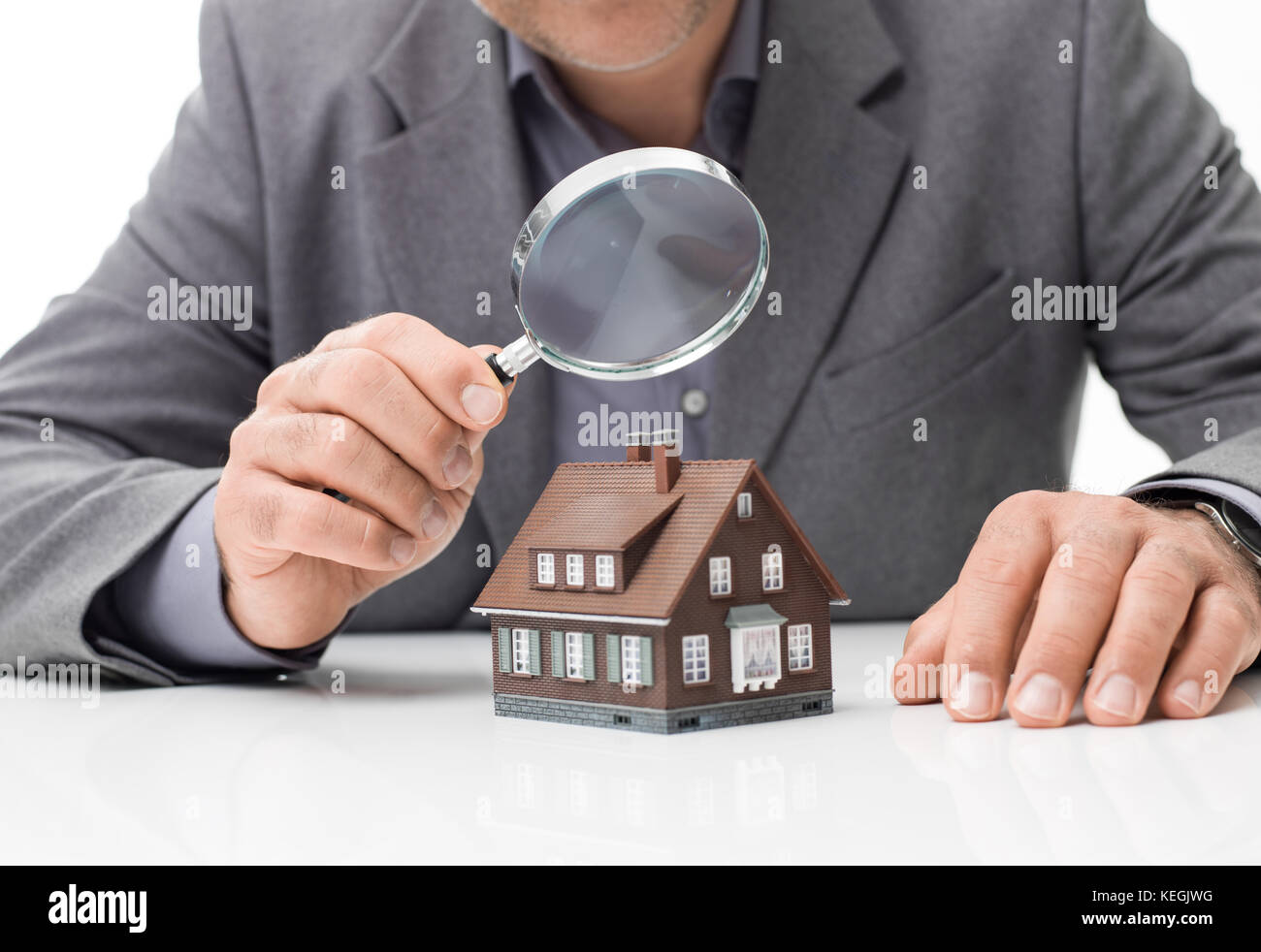 Inspector examining a house using a magnifying glass, house inspection and real estate concept