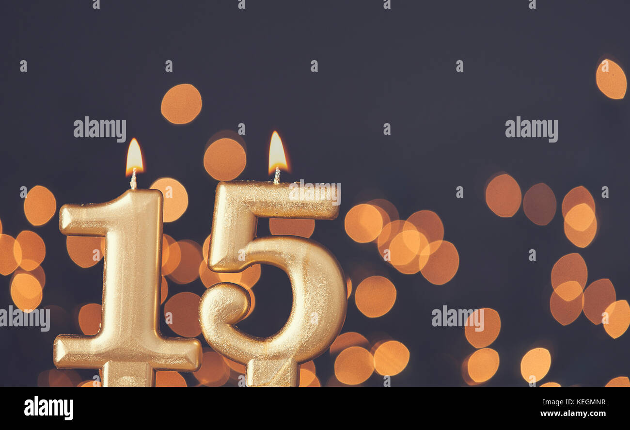 Gold number 15 celebration candle against blurred light background