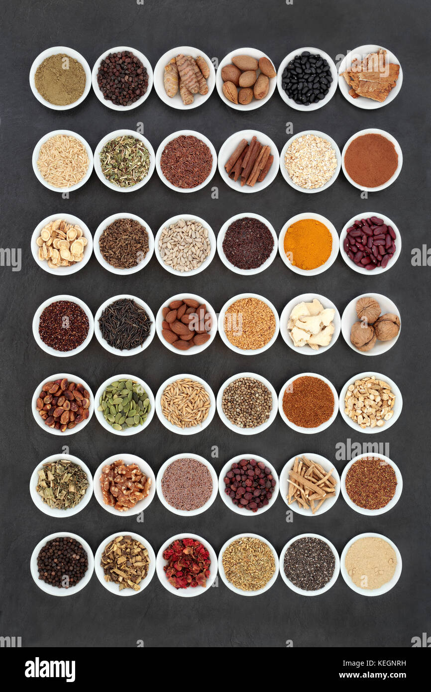 Healthy heart food collection with medicinal herbs used in alternative medicine. Large collection in porcelain bowls on slate background. Stock Photo