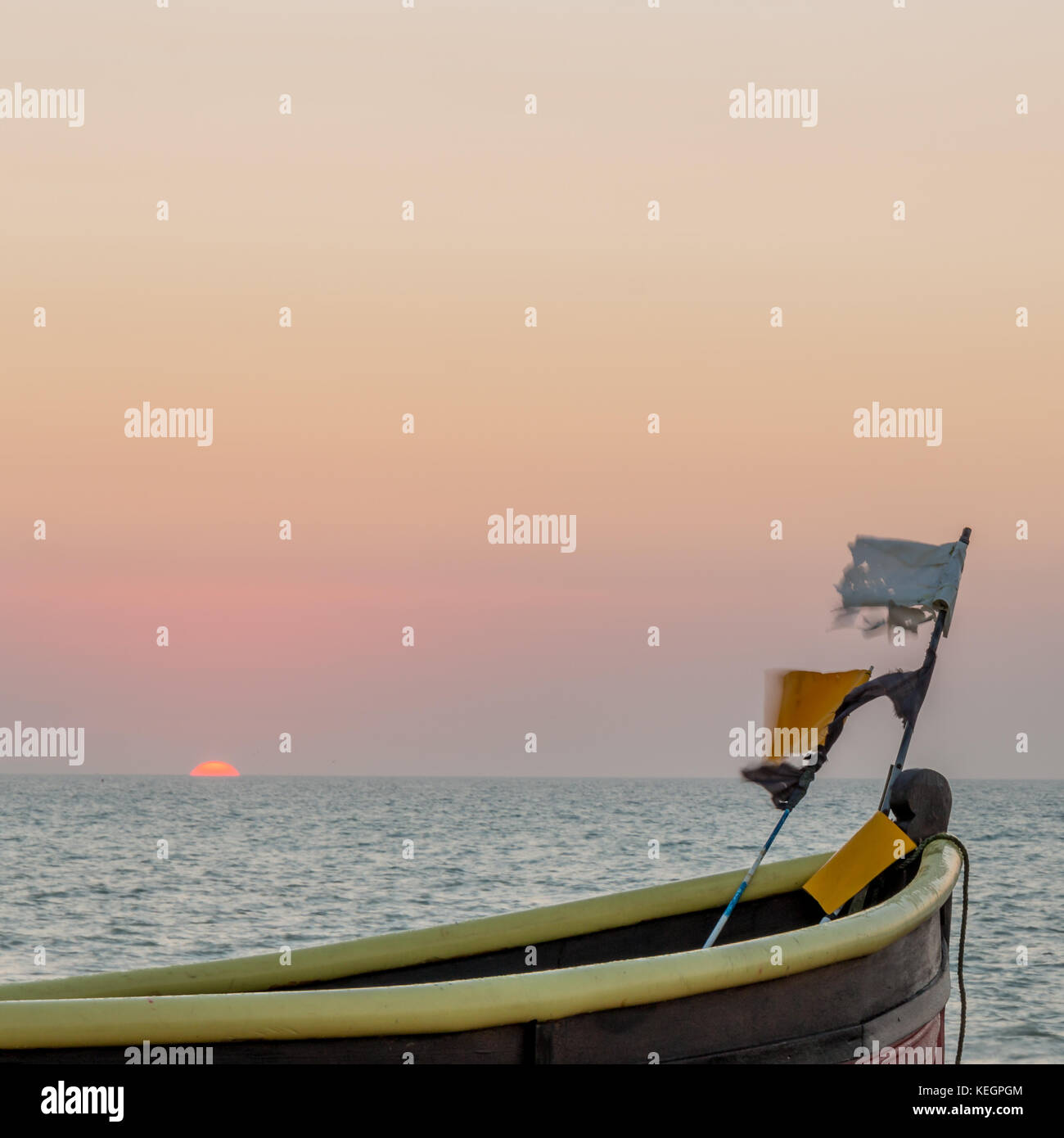 The top of a fishing boat with flags at the bow. The sea is behind and