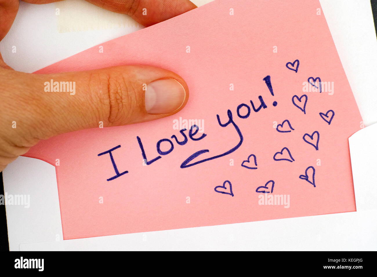 Woman hand taking out letter with text I Love You! from envelope. Close-up. Stock Photo