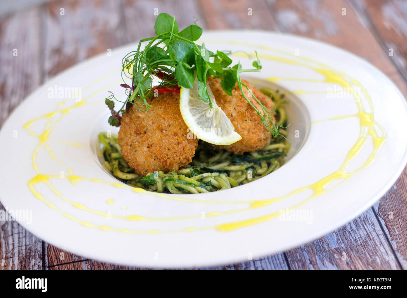 Crab cakes with pasta and courgette Stock Photo Alamy