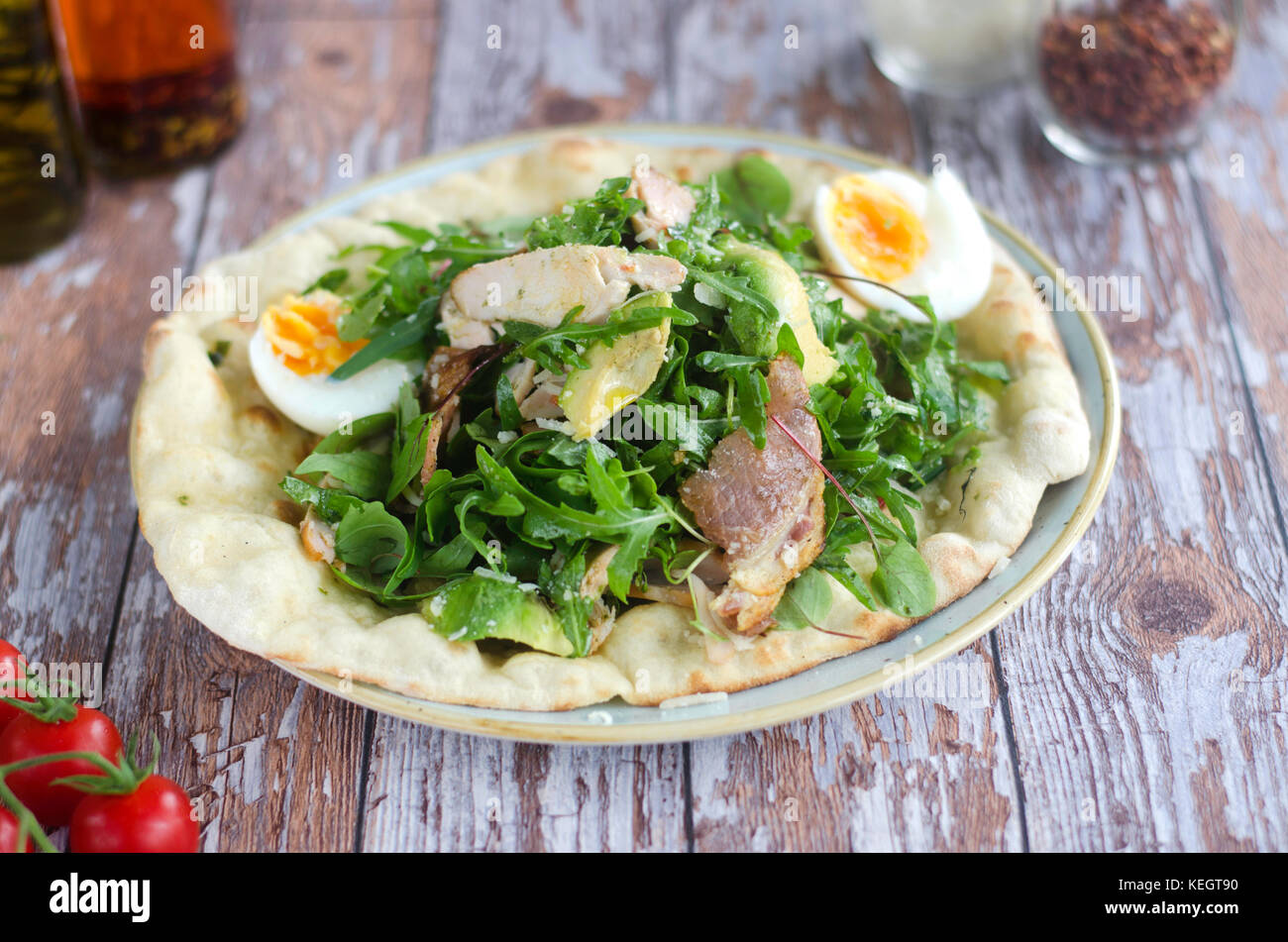 Pizza topped with chicken, boiled egg and rocket Stock Photo