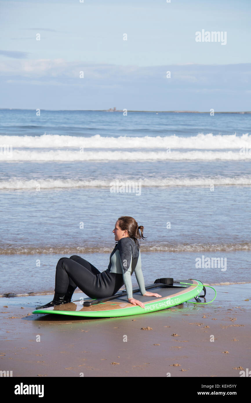 Surfing on Bamburgh beach, Northumberland, England, UK Stock Photo