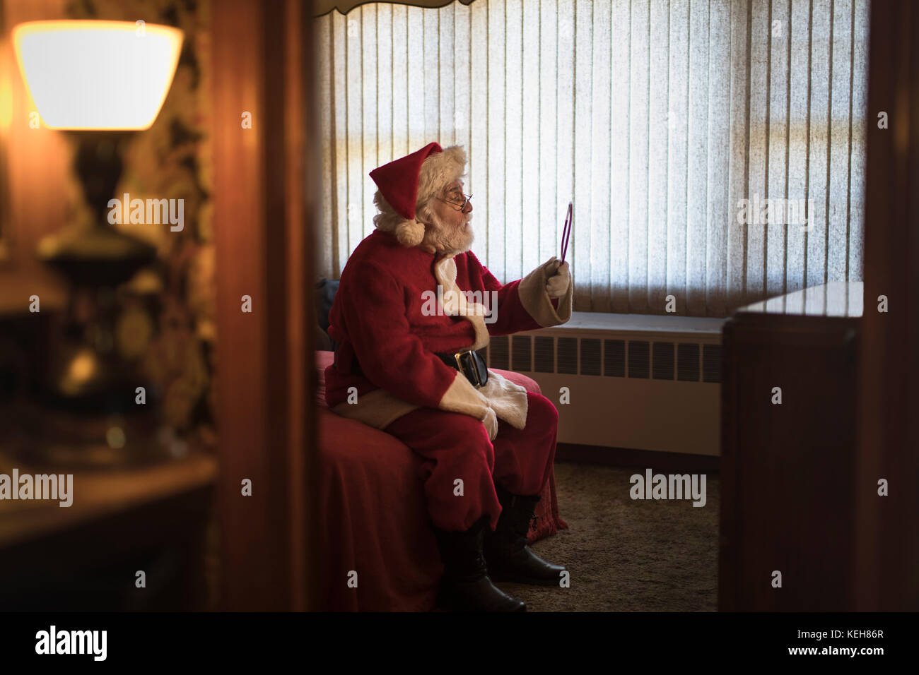 Depressed Caucasian Santa holding mirror on bed Stock Photo