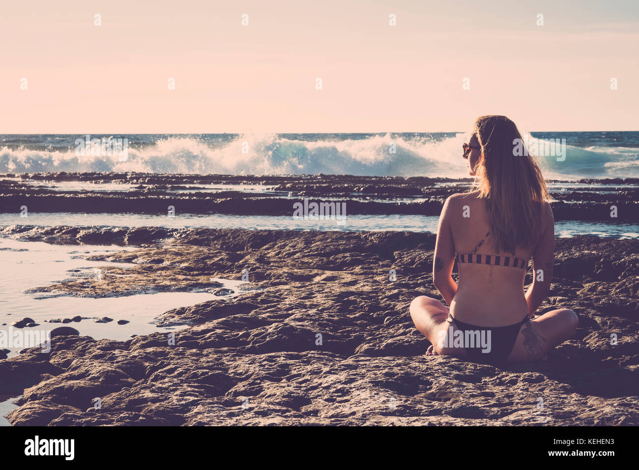 Caucasian woman sitting on beach wearing bikini Stock Photo
