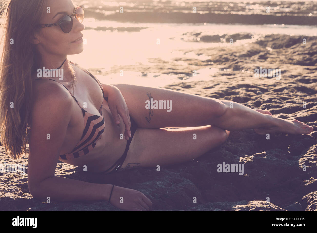 Caucasian woman laying on beach wearing bikini Stock Photo