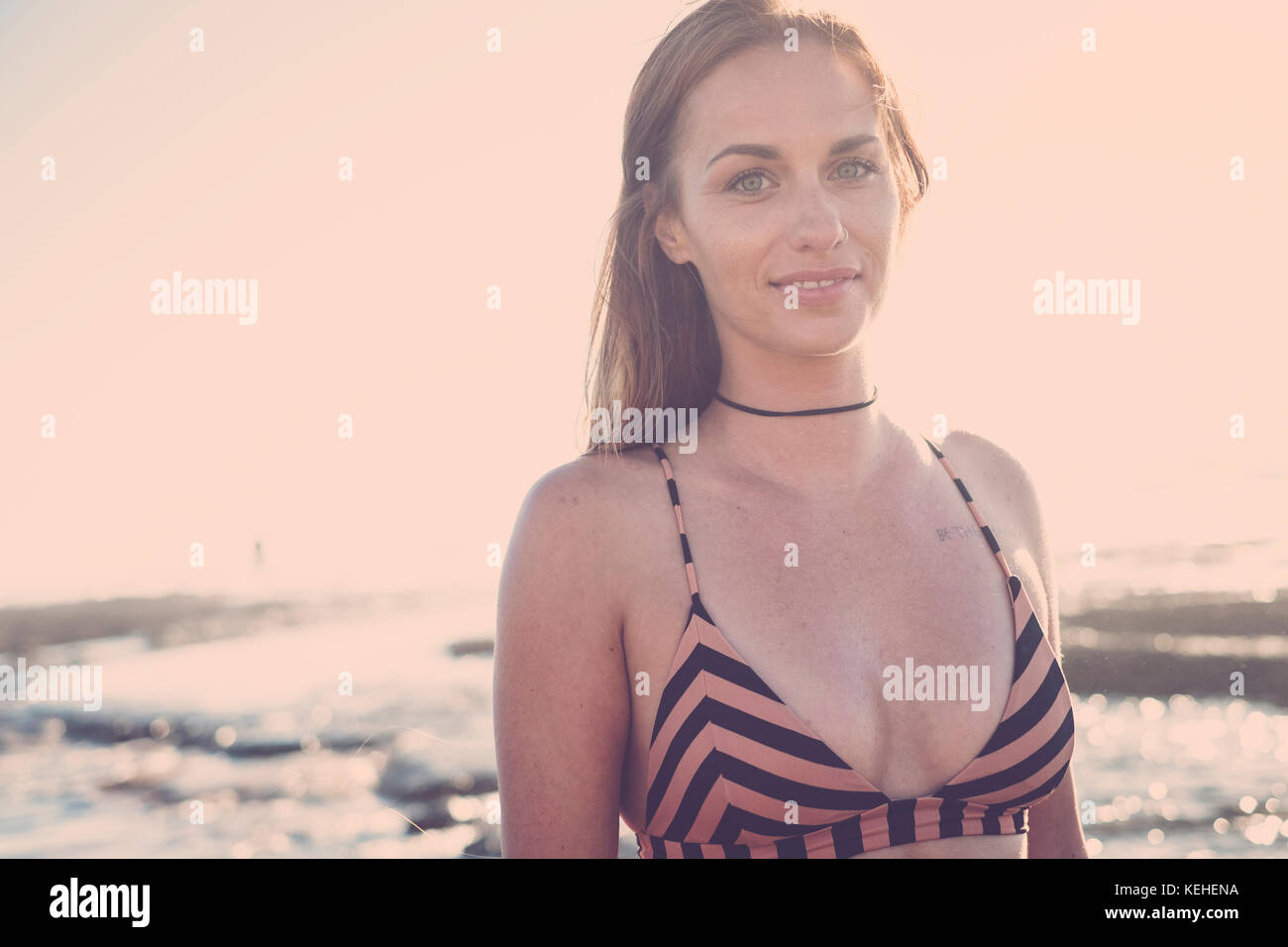 Smiling Caucasian woman wearing bikini on beach Stock Photo