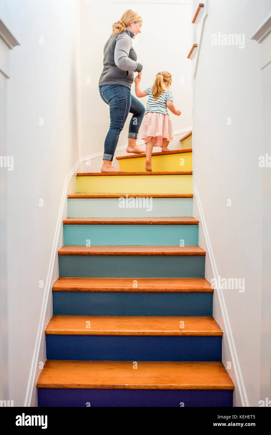Caucasian mother and daughter climbing multicolor staircase Stock Photo