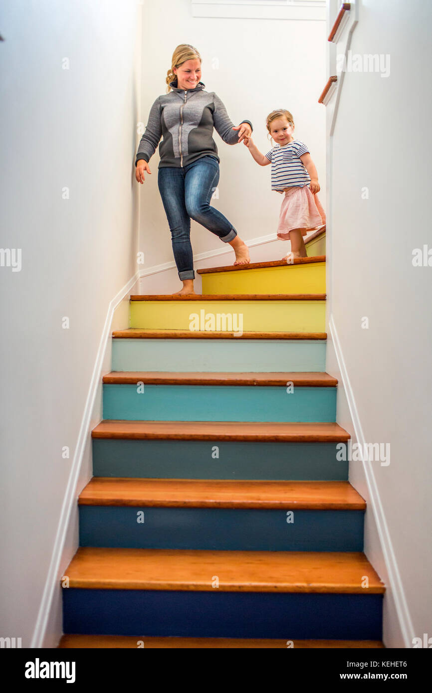 Caucasian mother and daughter descending multicolor staircase Stock Photo