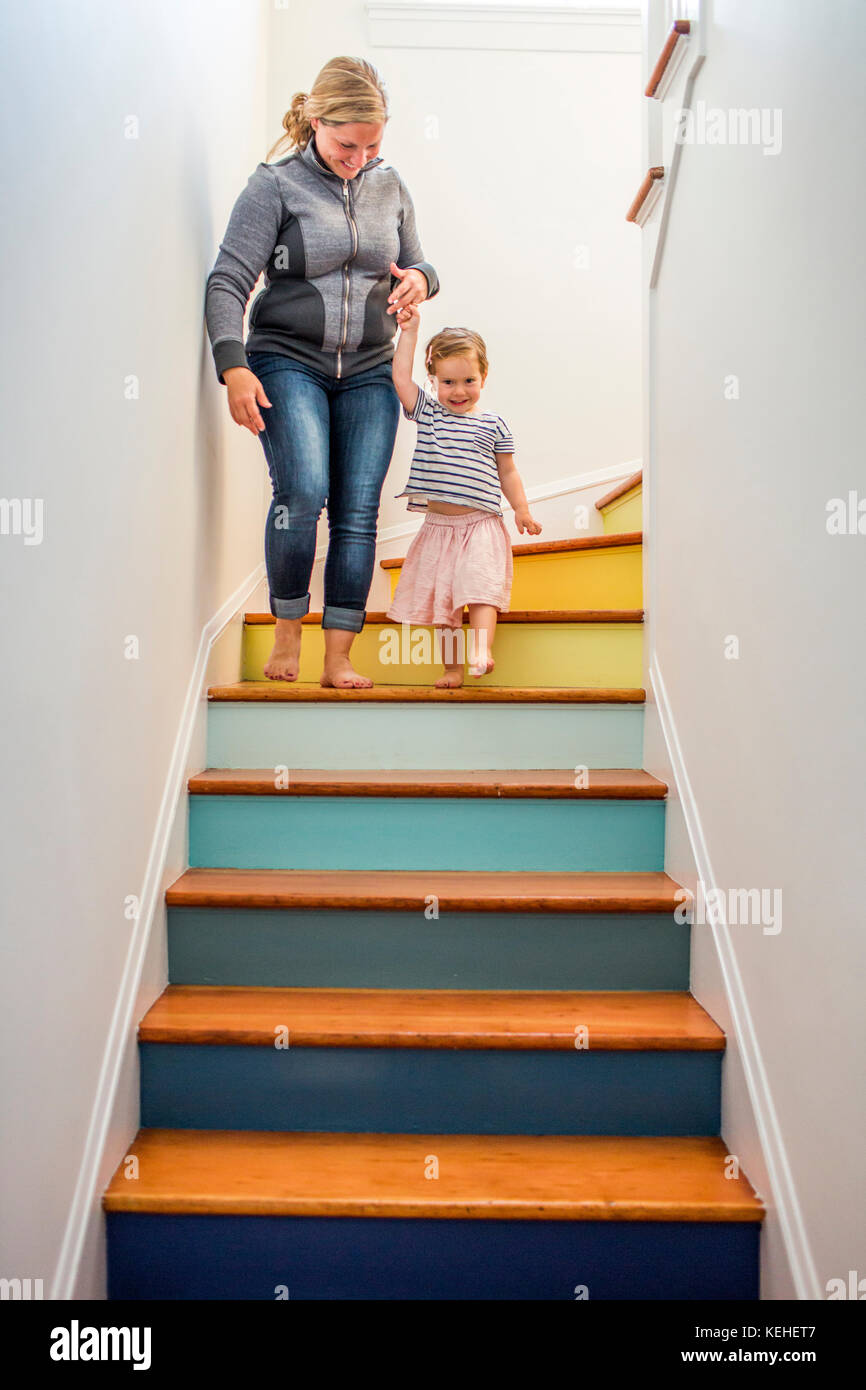 Caucasian mother and daughter descending multicolor staircase Stock Photo