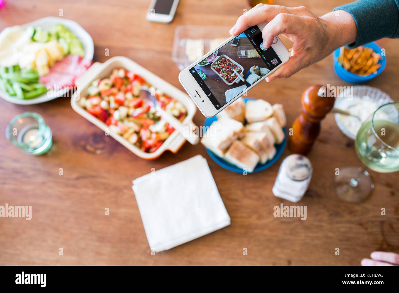 Woman photographing appetizers on table with cell phone Stock Photo