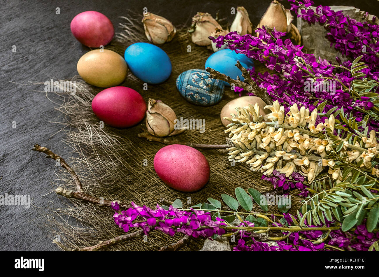Bouquet of wild flowers and colored Easter eggs on a black background ...