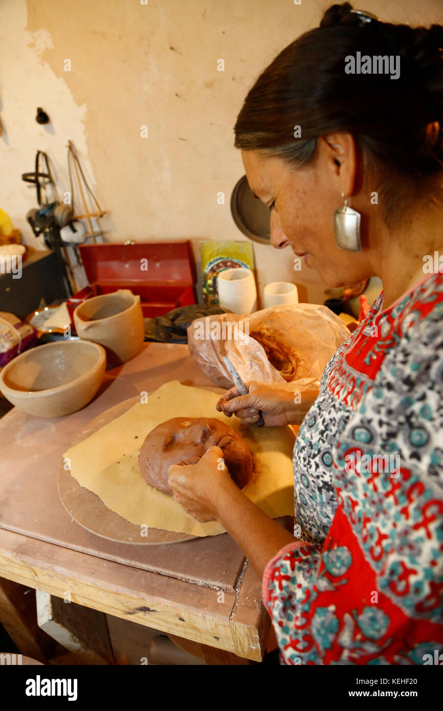 Mixed race woman shaping clay mask in art studio Stock Photo