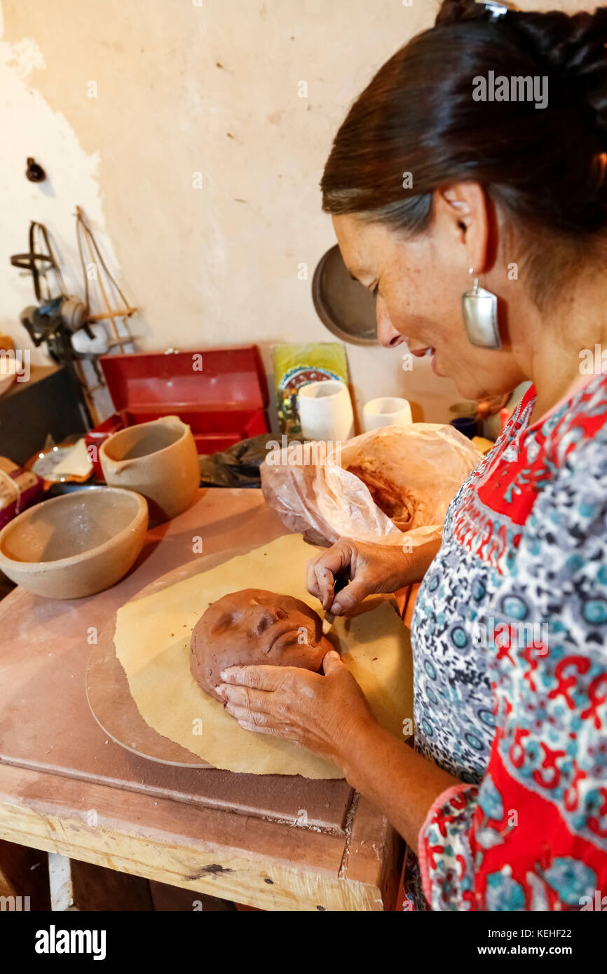 Mixed race woman shaping clay mask in art studio Stock Photo