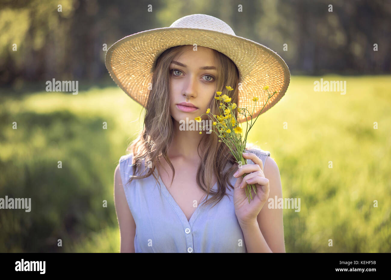Caucasian woman wearing hat holding wildflowers Stock Photo