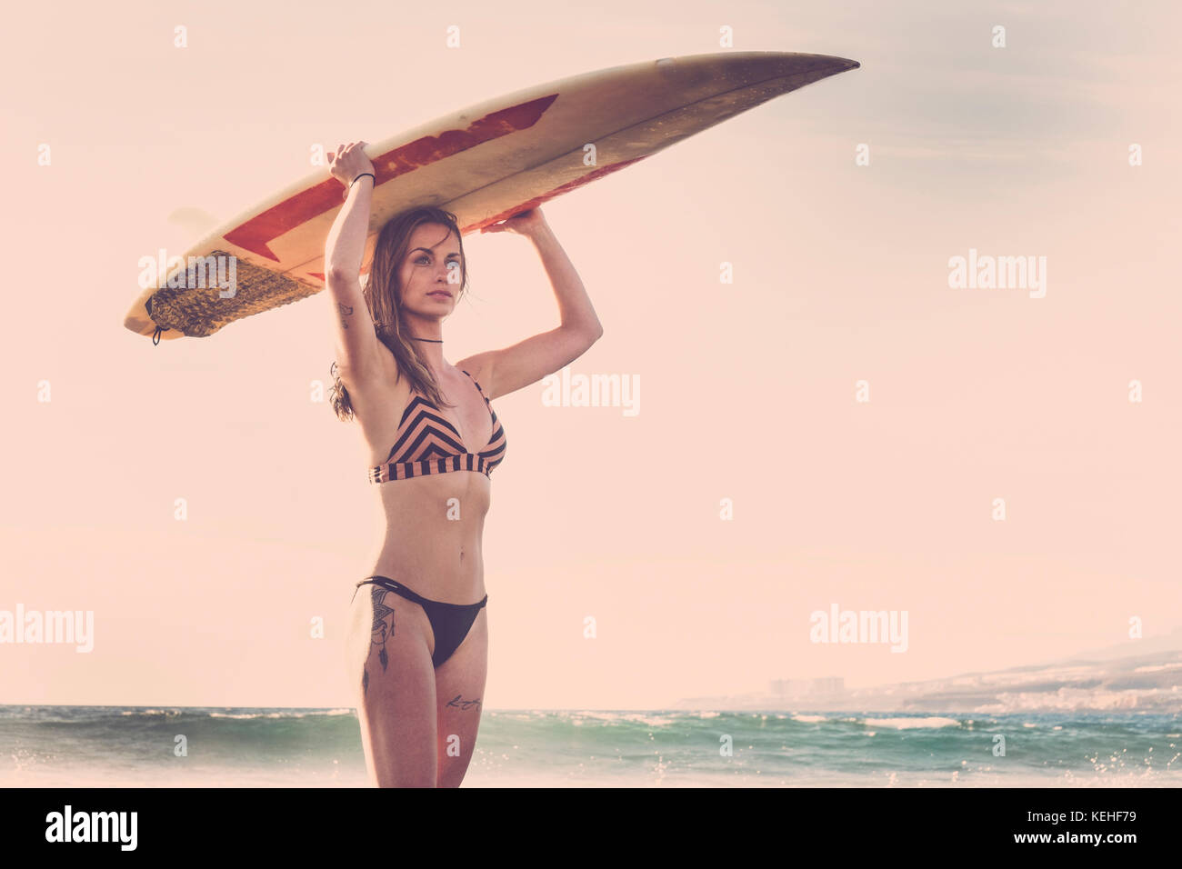 Caucasian woman standing on beach holding surfboard Stock Photo