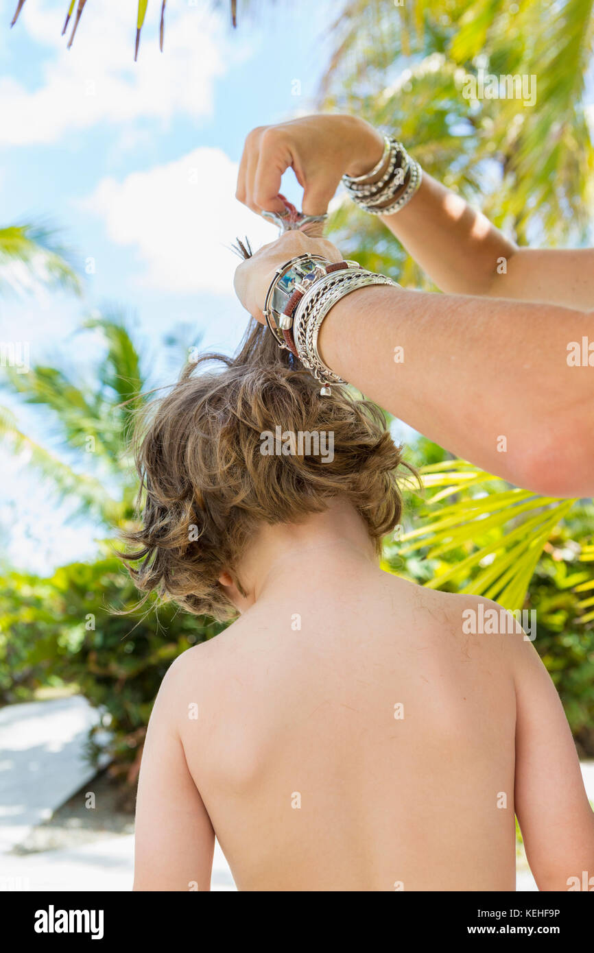 Caucasian mother cutting hair of son outdoors Stock Photo