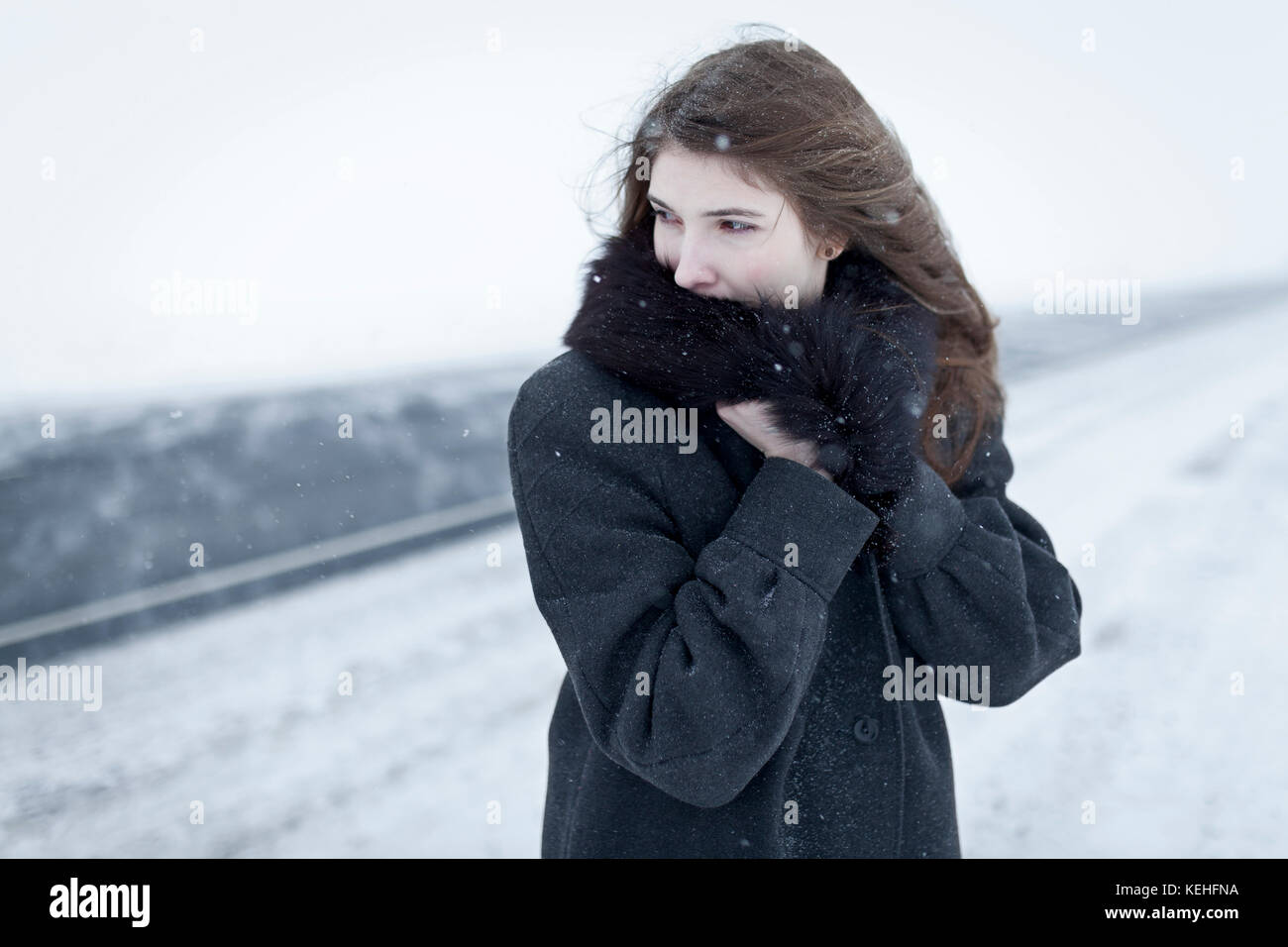 Caucasian woman nestling in fur collar outdoors in winter Stock Photo