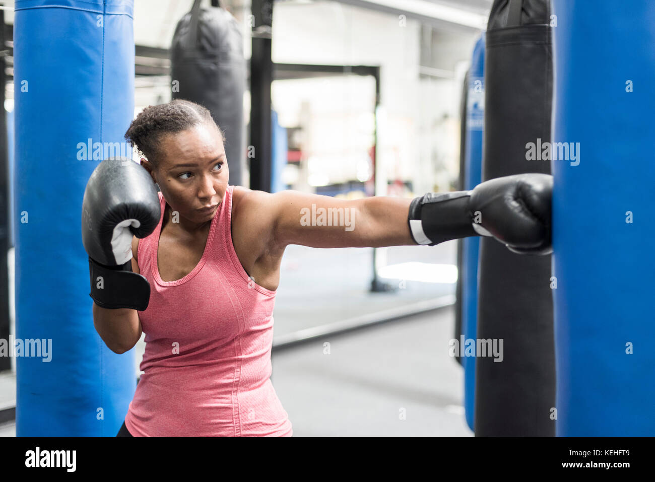 Black woman wearing boxing gloves hitting punching bag Stock Photo Alamy