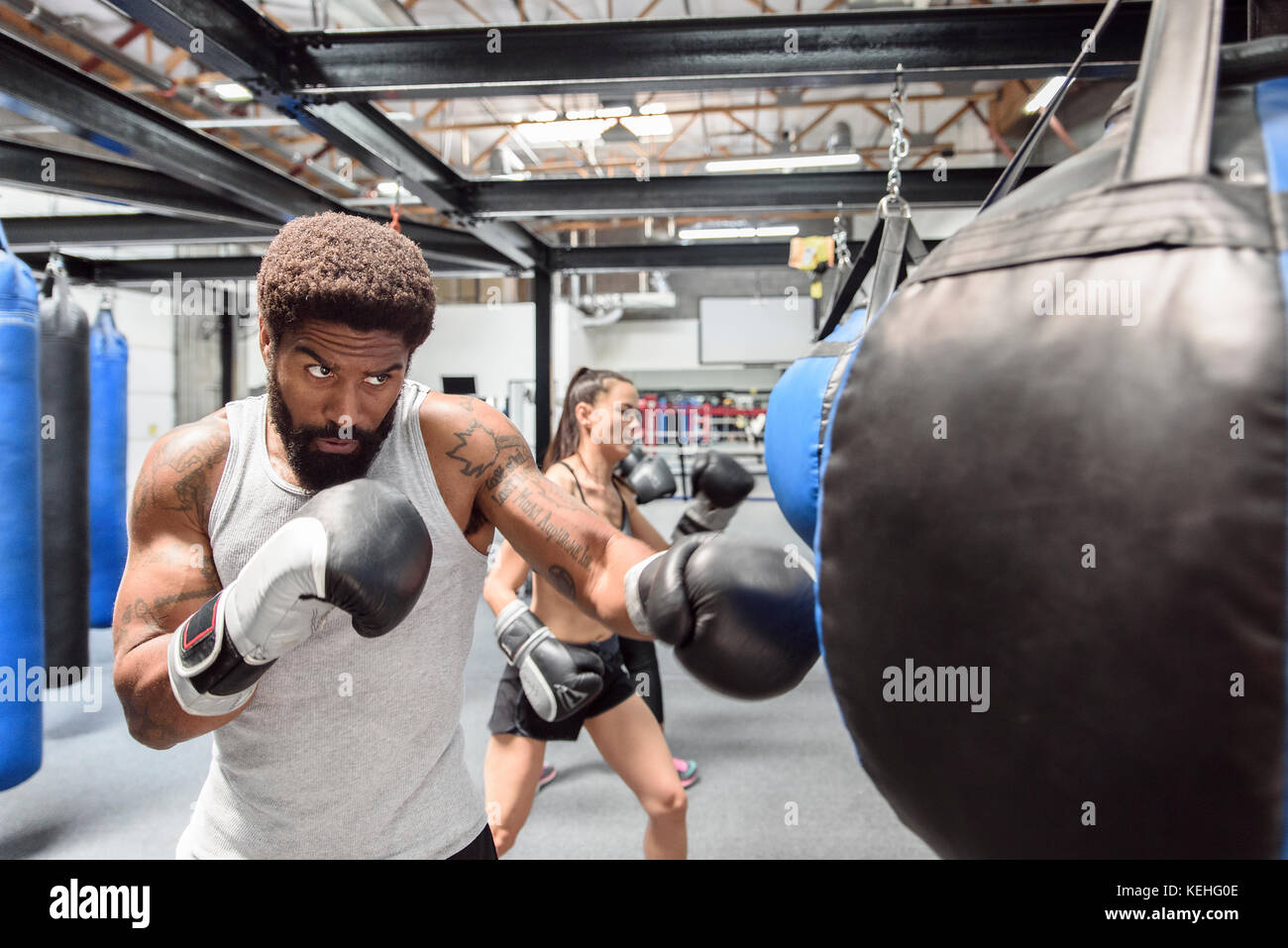 Man and women wearing boxing gloves hitting heavy bags Stock Photo Alamy