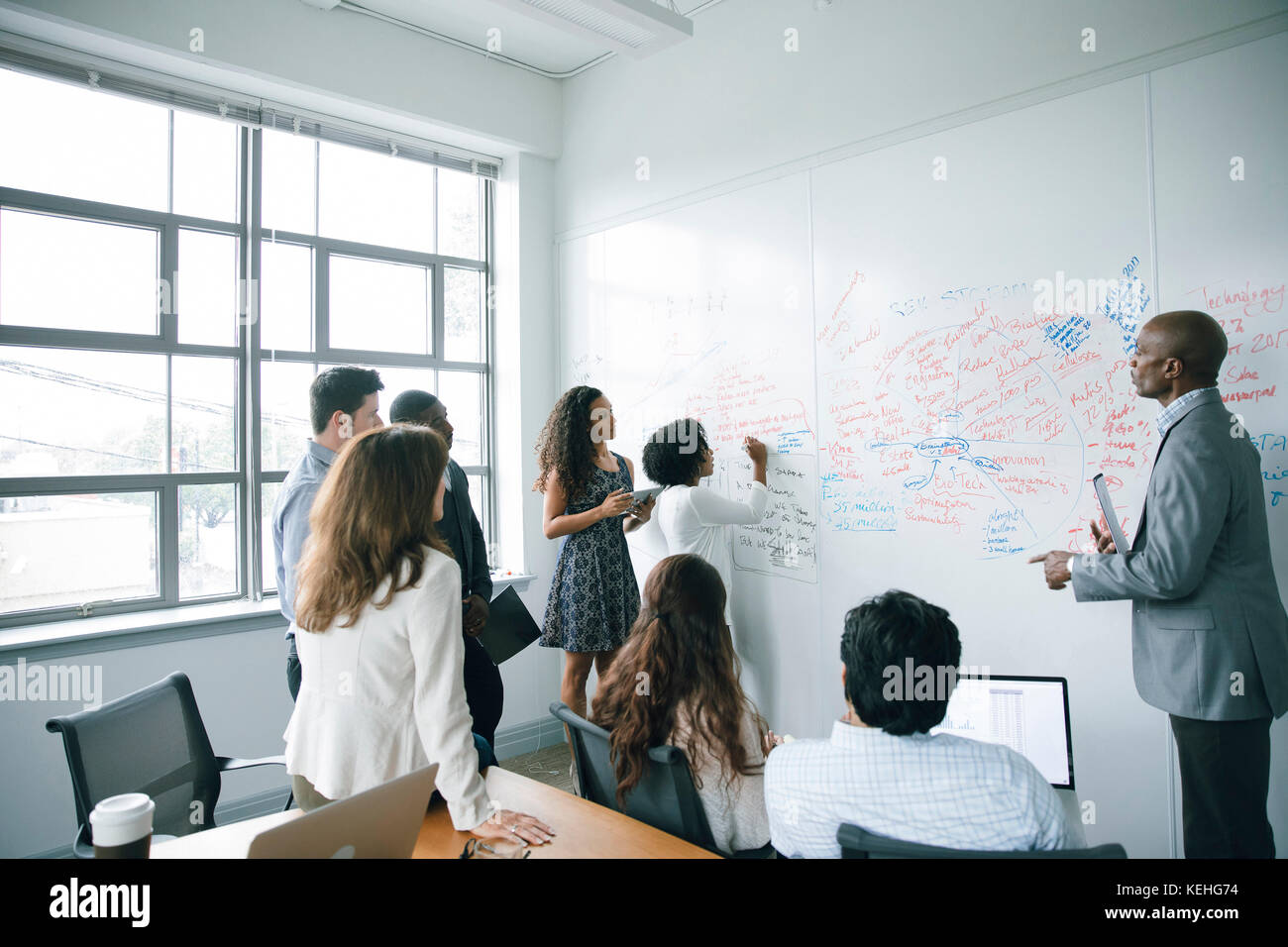 Businesswoman writing on whiteboard in meeting Stock Photo