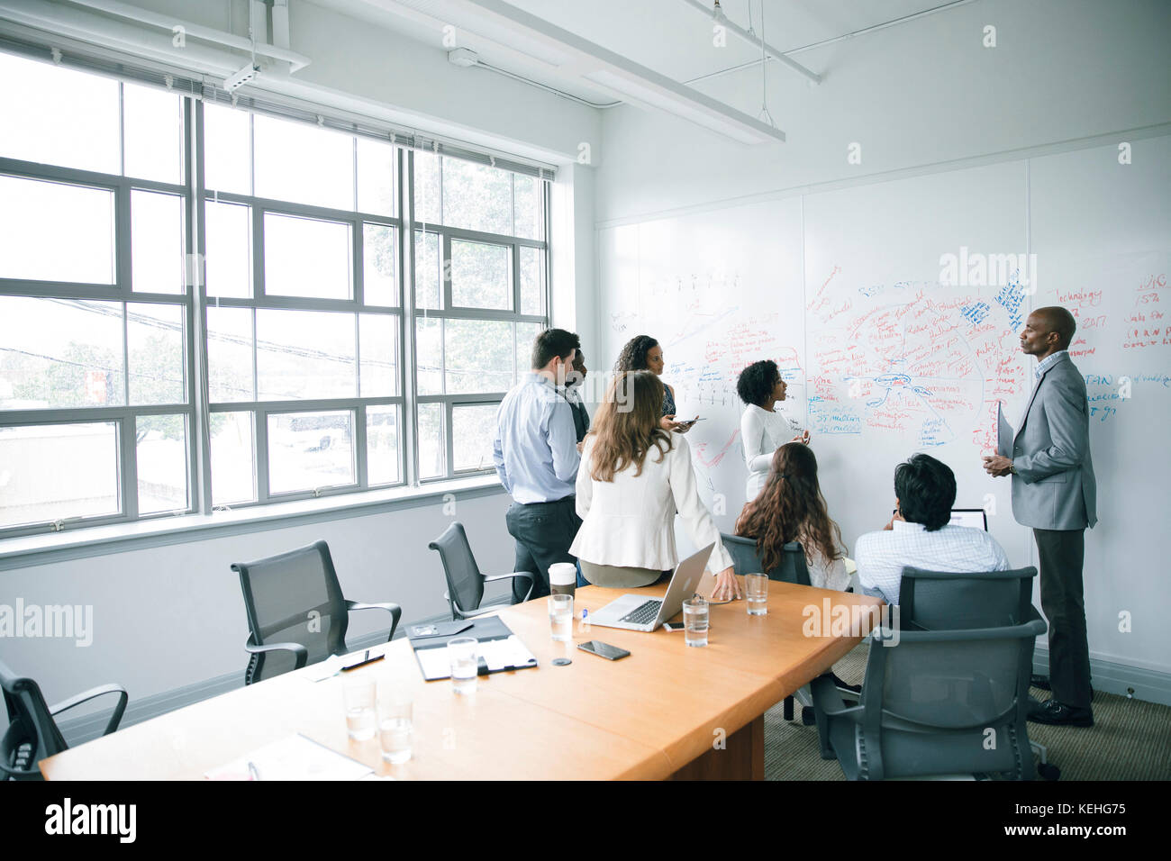 Business people talking near whiteboard in meeting Stock Photo