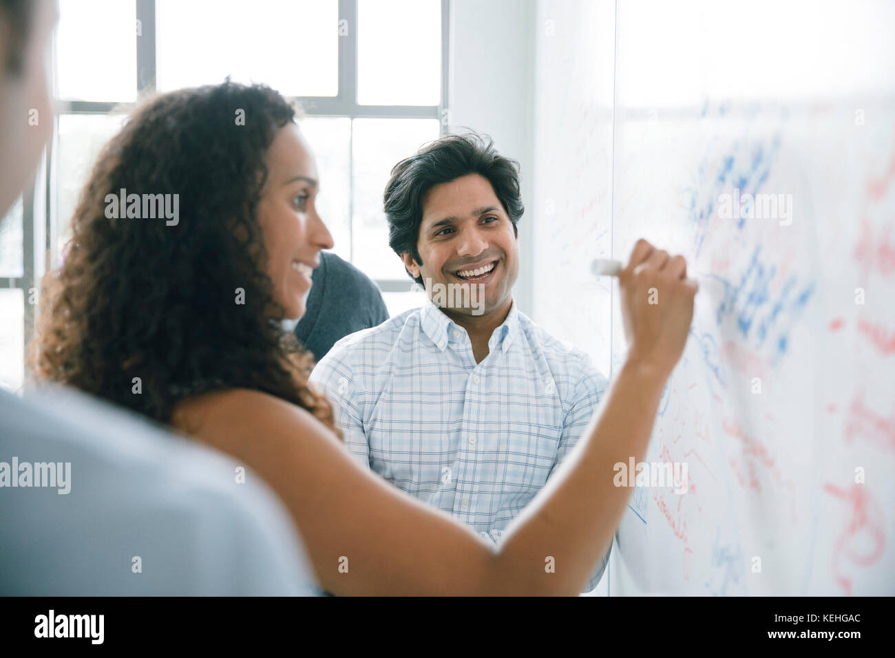 Businesswoman writing on whiteboard in meeting Stock Photo
