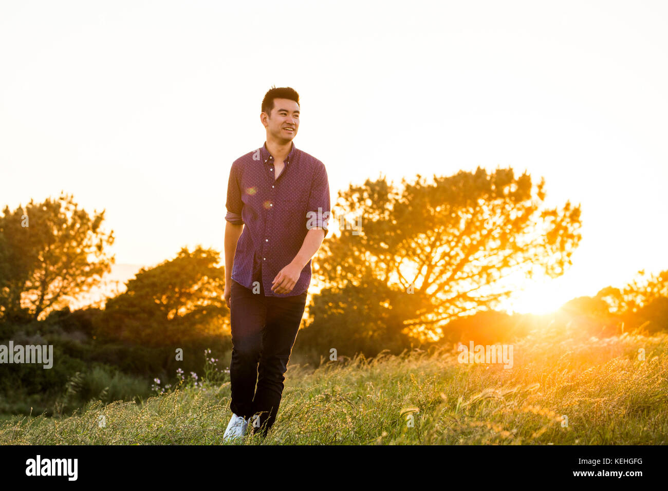 Smiling Chinese man walking on hill Stock Photo