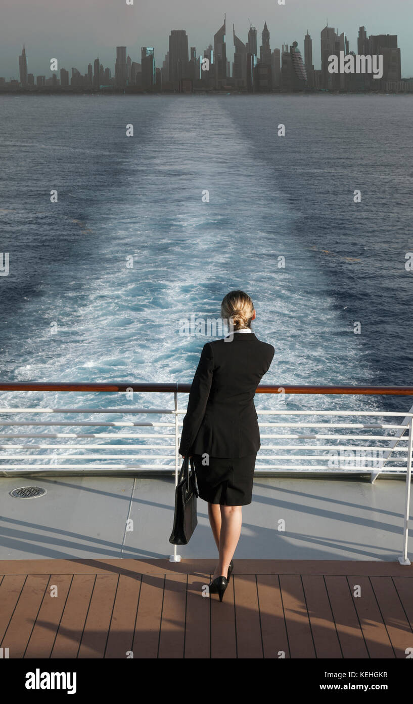 Caucasian businesswoman on boat leaving city Stock Photo