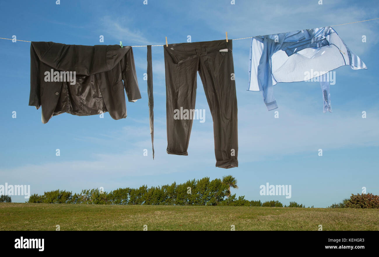 Wet business suit hanging on clothesline in field Stock Photo