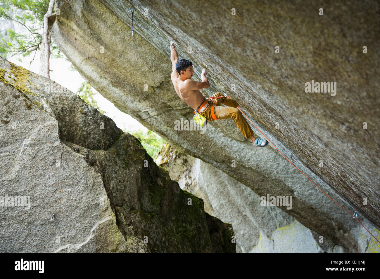 Mixed race boy rock climbing Stock Photo