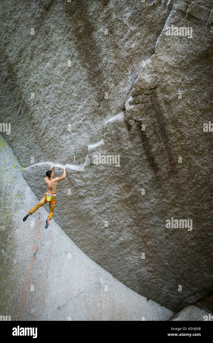 Mixed race boy hanging from rock Stock Photo